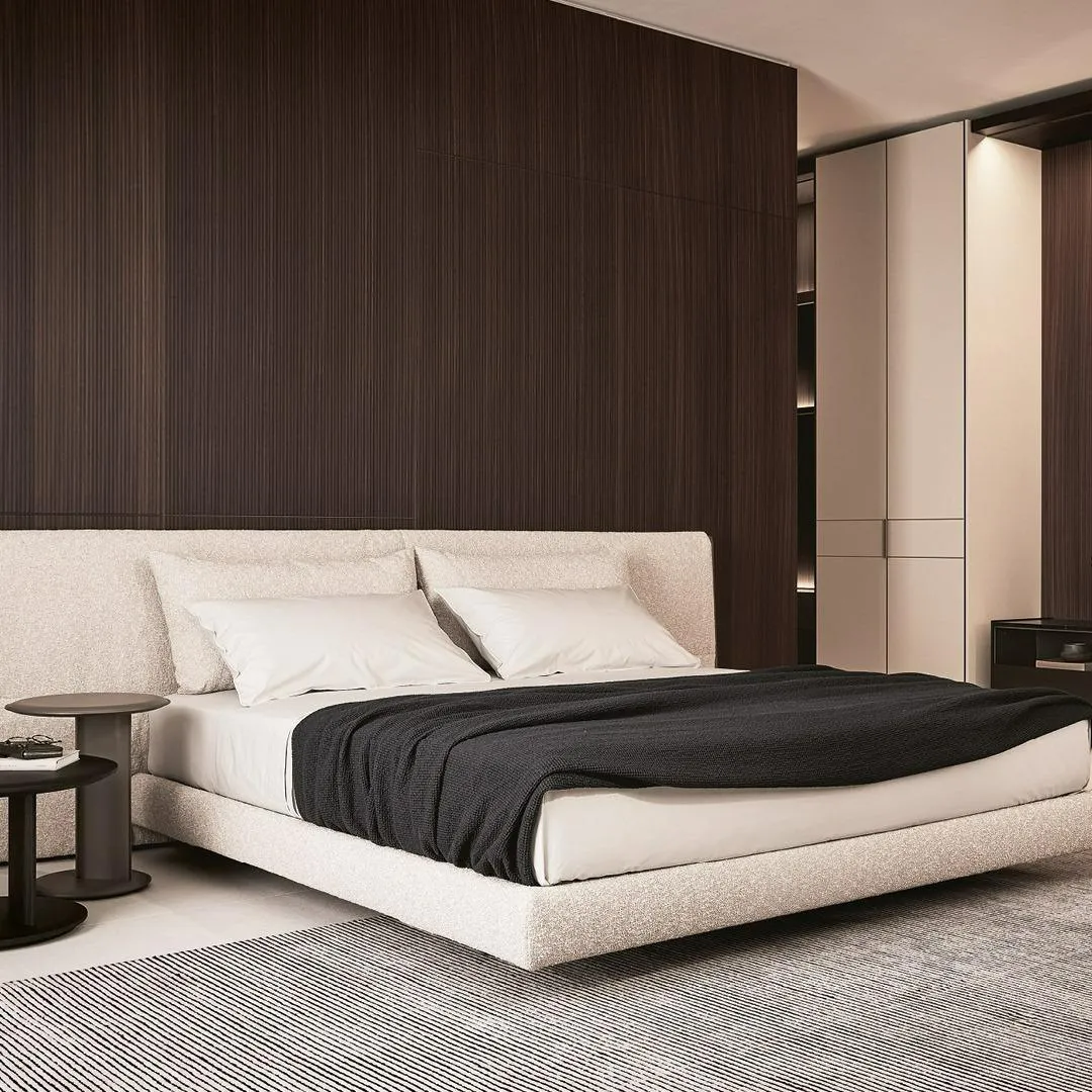 Contemporary minimalist bedroom design featuring a sleek upholstered bed and dark wood accents, Italian style furniture in Oman.
