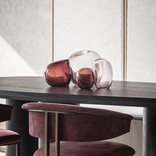 Artistic hand-blown glass decorative objects in ruby tones, premium tabletop accessories at Ajwaad Palace luxury showroom, Oman.
