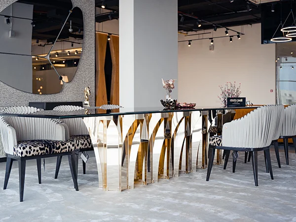 Luxury Roberto Cavalli Home Interiors dining table with gold finish and leopard print chairs at Ajwaad Palace showroom in Muscat, Oman.